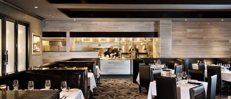 A restaurant with a central bar area, multiple dining tables with chairs, and a patterned carpet.