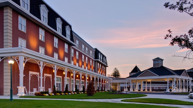 A multi-story hotel with a covered walkway and a lawn in front. - Saratoga Casino Hotel (Saratoga Springs)