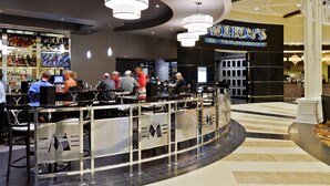 A modern restaurant with a bar area, featuring a chandelier, seating, and a visible sign for 'Delton's The Steakhouse'. - Saratoga Casino Hotel (Saratoga Springs)
