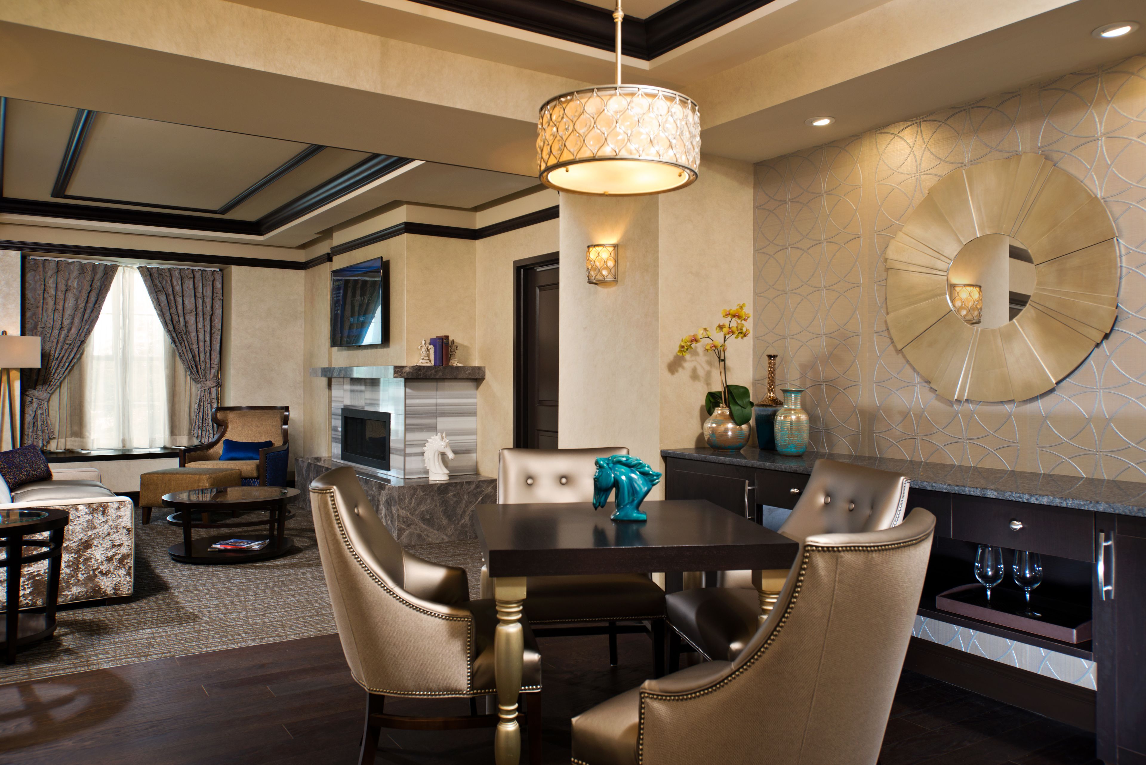 A modern dining area with a round table, leather chairs, and a chandelier.