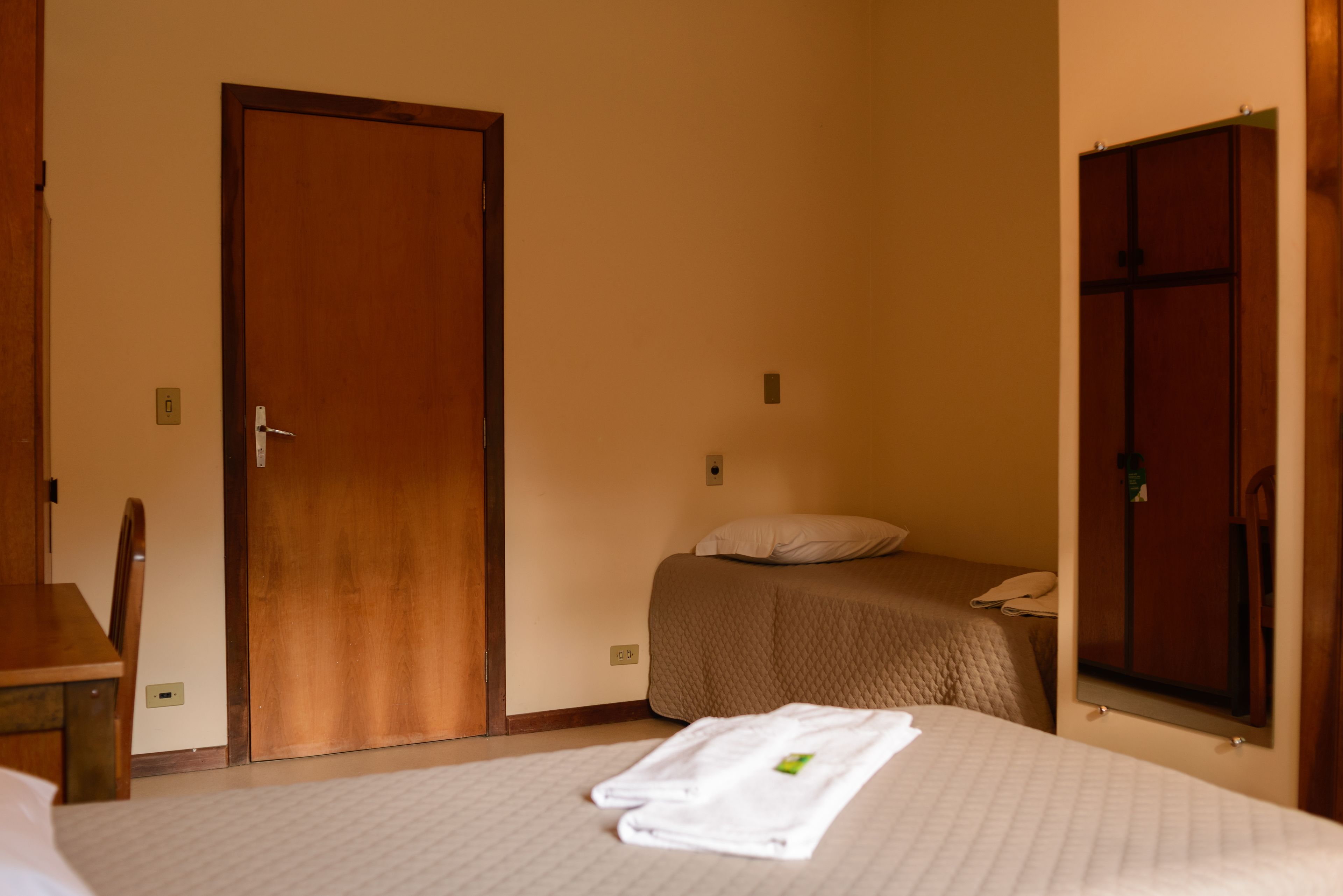 Ein Hotelzimmer mit Bett, Nachttisch, Stuhl, Kleiderschrank und einer Tür.