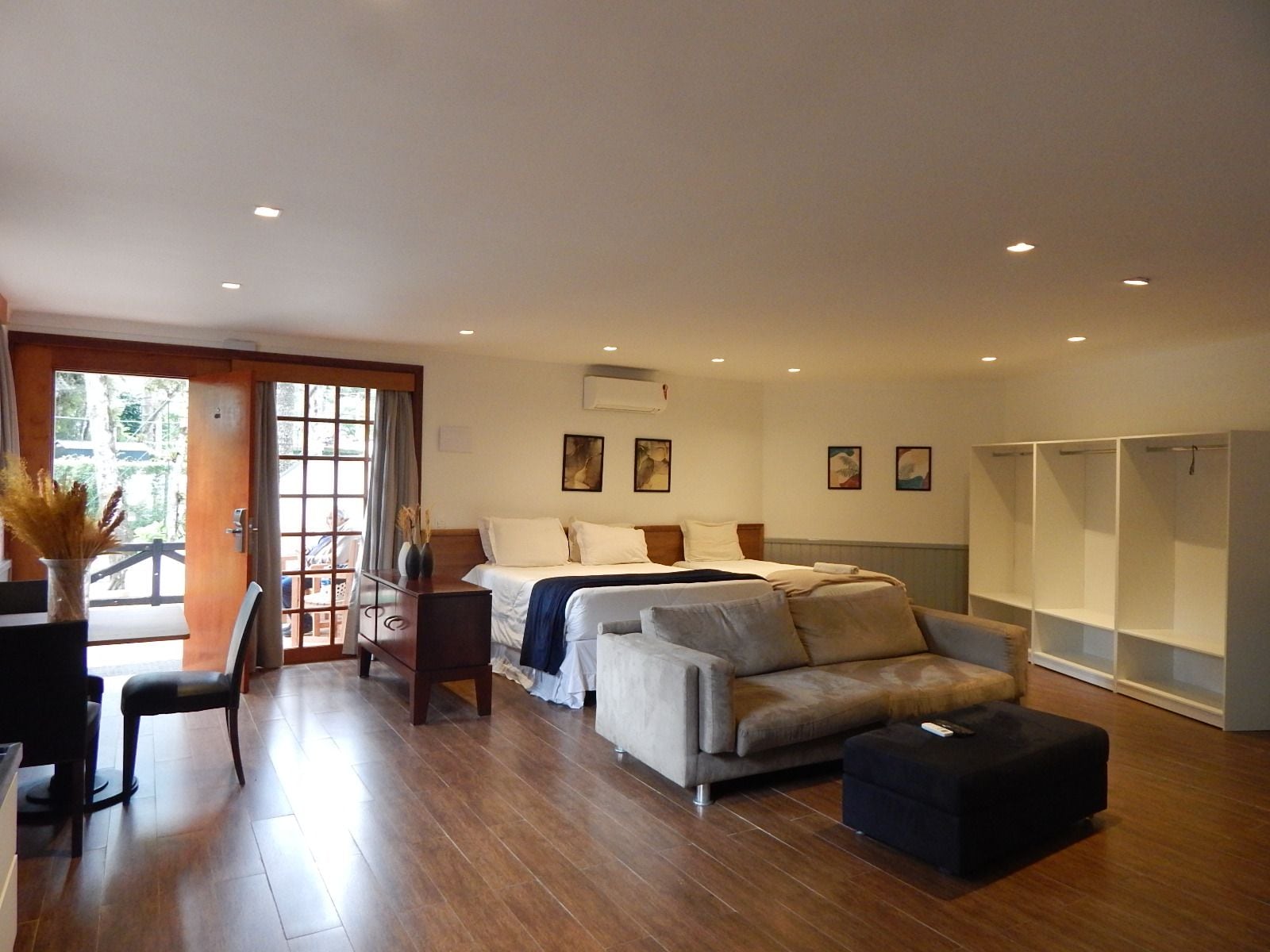 A spacious room with a bed, a sofa, a dining area, and a wardrobe.