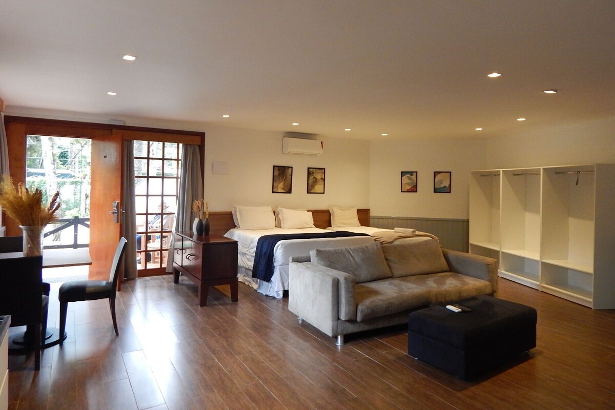 A spacious room with a bed, a sofa, a dining area, and a wardrobe.
