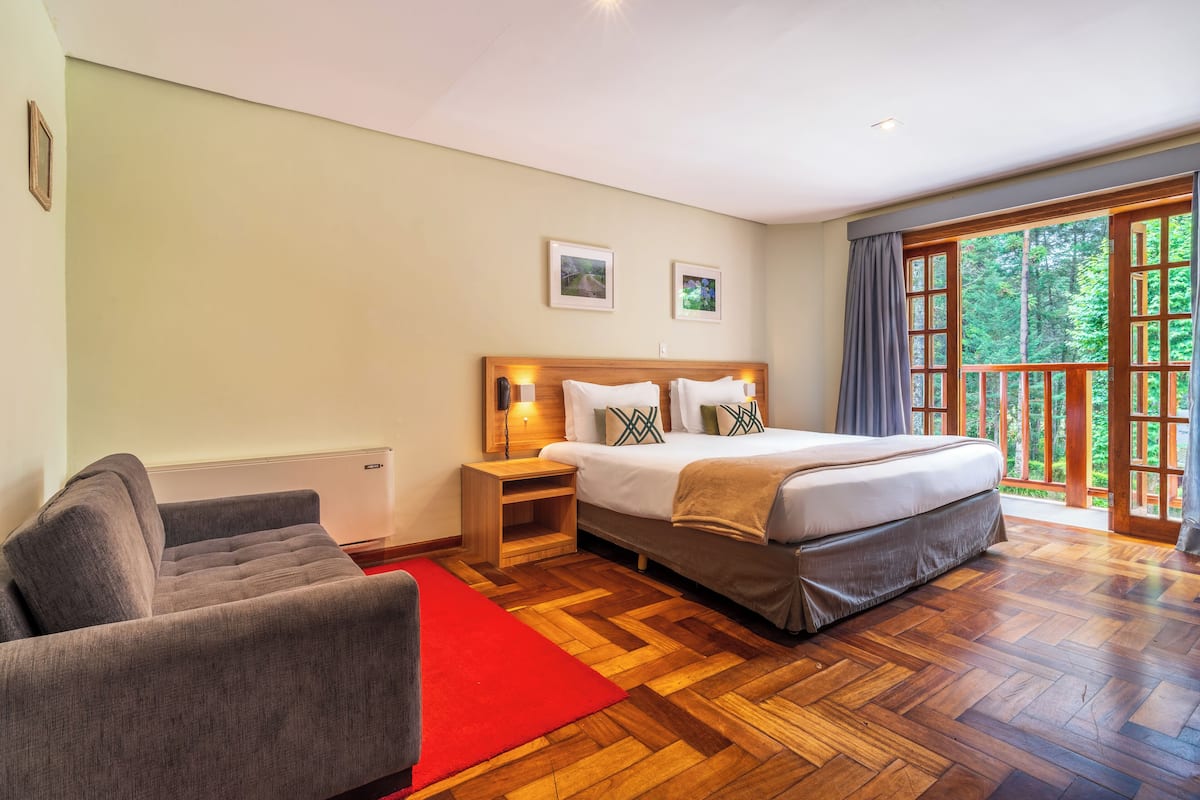 Un dormitorio con cama, mesita de noche y un sofá gris.