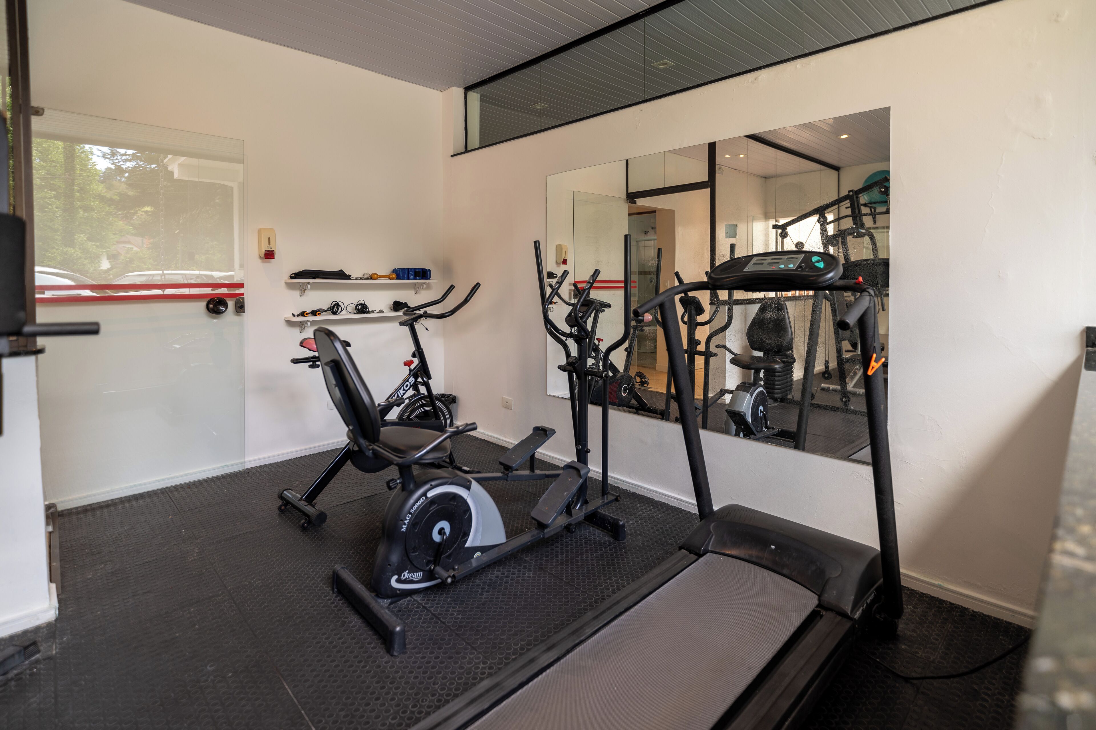 A gym with cardio machines, a mirrored wall, and a treadmill.