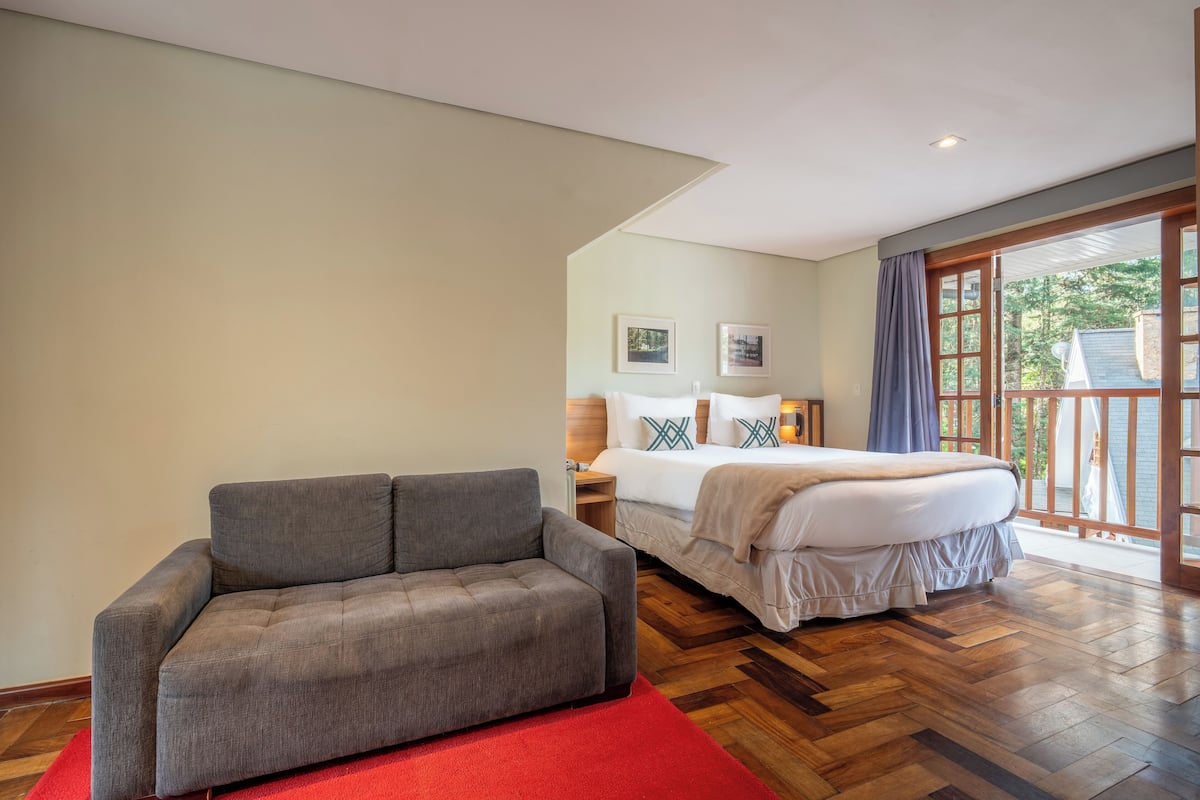 Un dormitorio con una cama, un sofá gris y una alfombra roja.