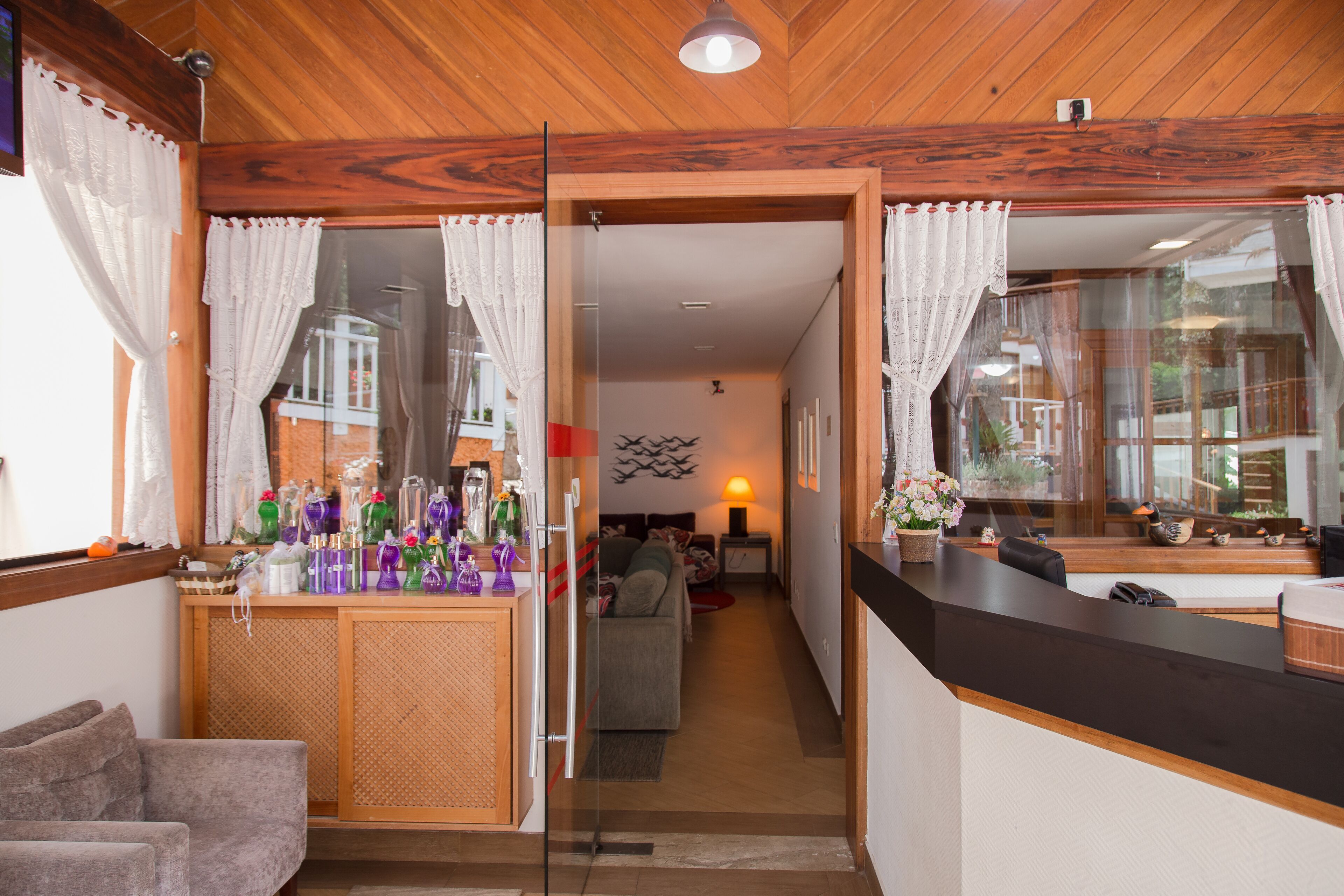 Una habitación de hotel moderna con techo de madera, un separador de vidrio que divide la sala de estar del dormitorio y una pequeña cocina.