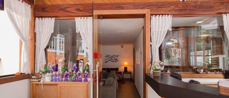 Una habitación de hotel moderna con techo de madera, un separador de vidrio que divide la sala de estar del dormitorio y una pequeña cocina.