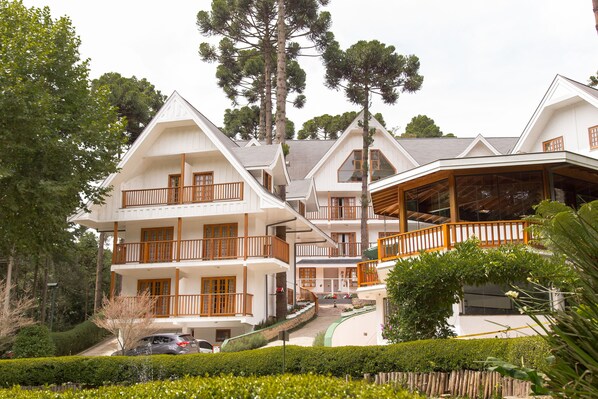A multi-story hotel with balconies, a covered outdoor area, and a well-maintained garden. - Pousada Campos dos Holandeses (Campos do Jordão)