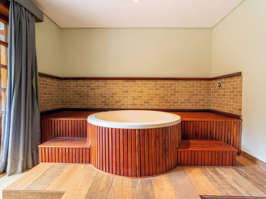 Una habitación de esquina con un rincón de estar con banco de madera y una bañera hidromasaje integrada.