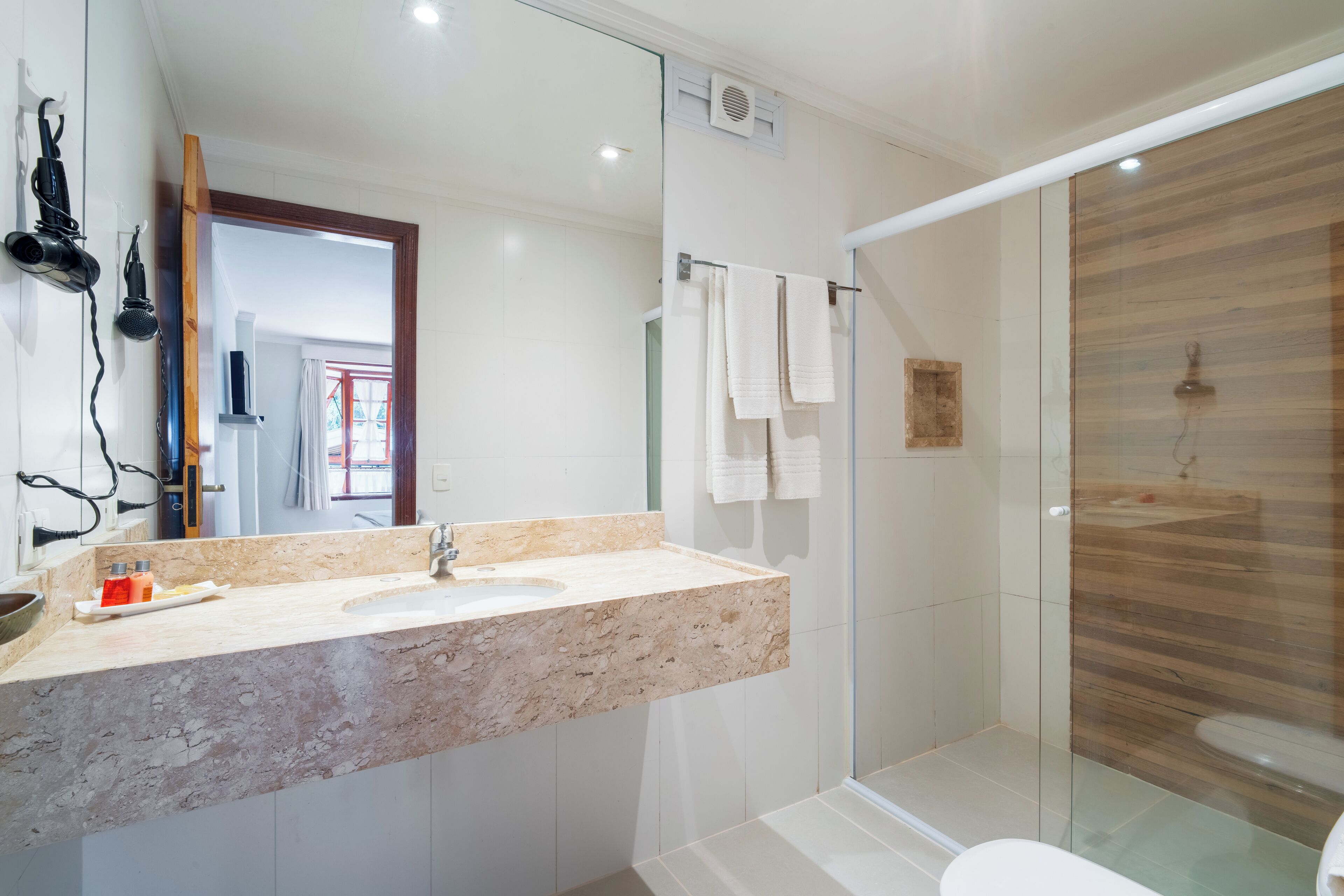 A modern bathroom with a marble sink, glass shower enclosure, and a large mirror.