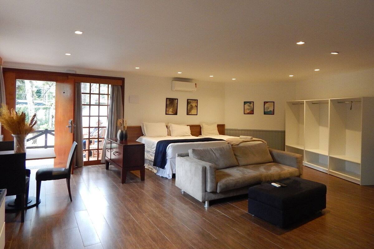 Una habitación amplia con cama, sofá, comedor y armario.