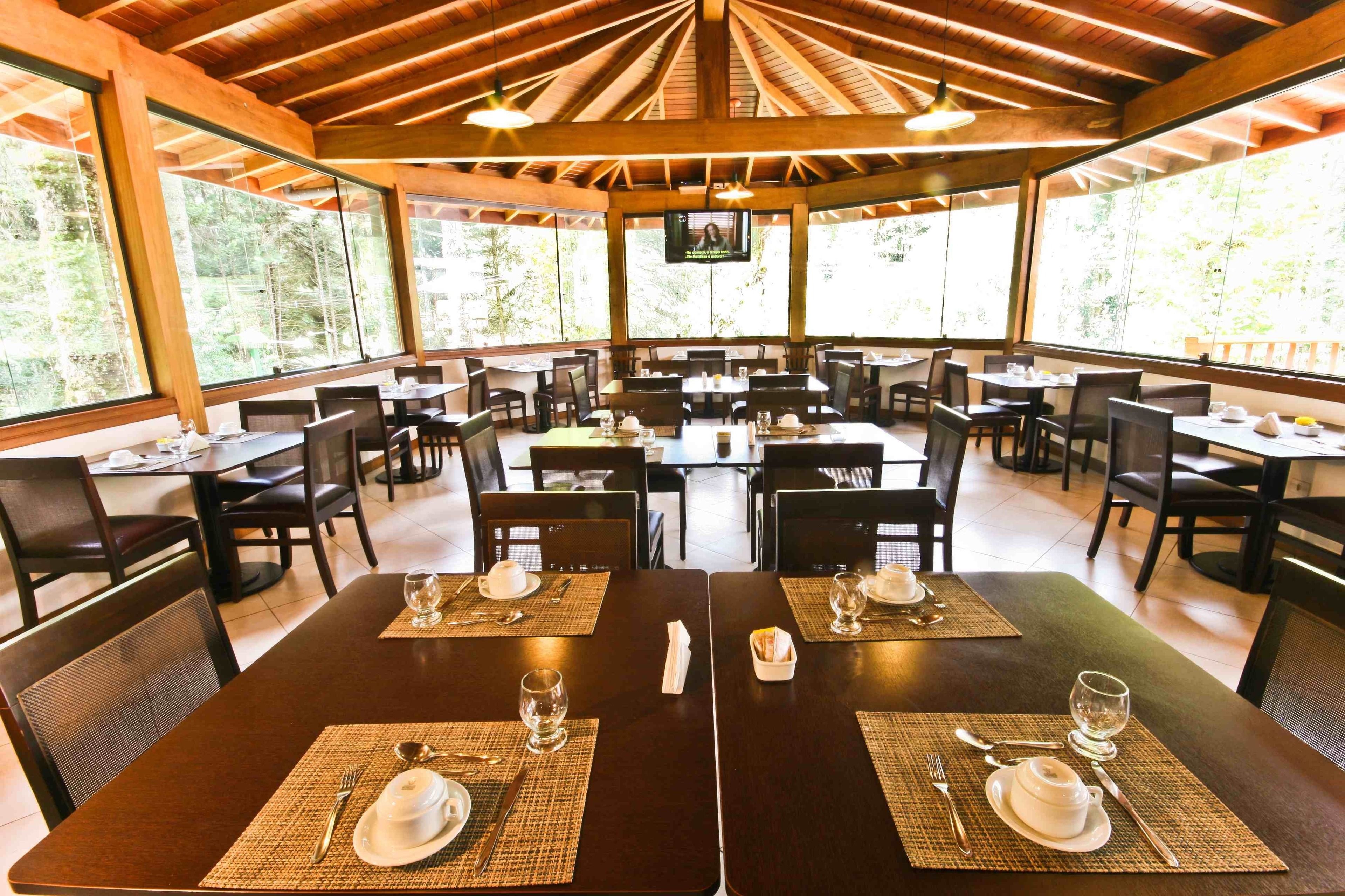 A restaurant with multiple tables, each set with cutlery, plates, and glasses.