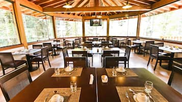 Un restaurante con varias mesas, cada una dispuesta con cubiertos, platos y vasos.