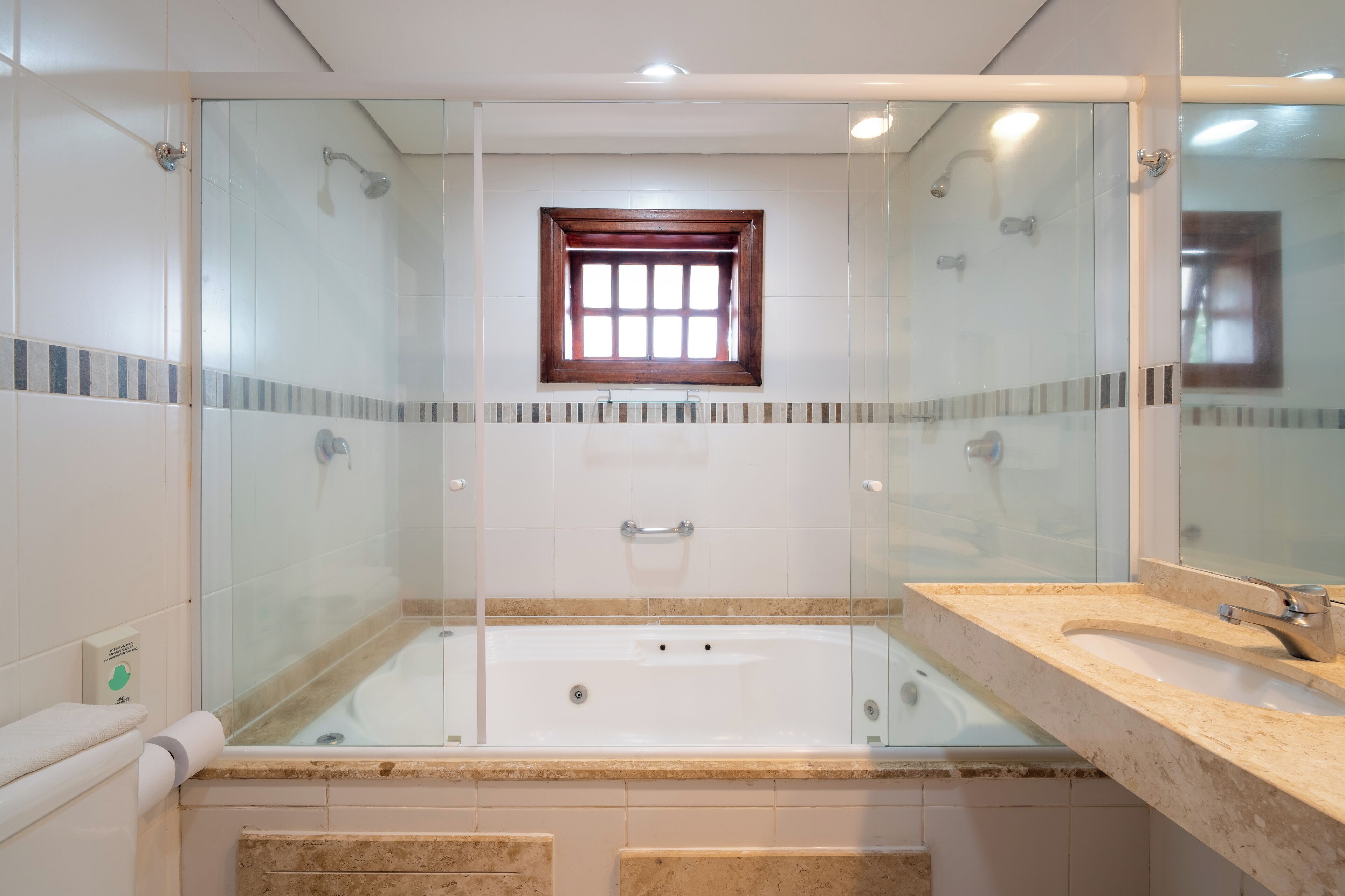 Ein modernes Badezimmer mit einer gläsernen Duschkabine, einer integrierten Badewanne und einem Waschtisch mit Spiegel.