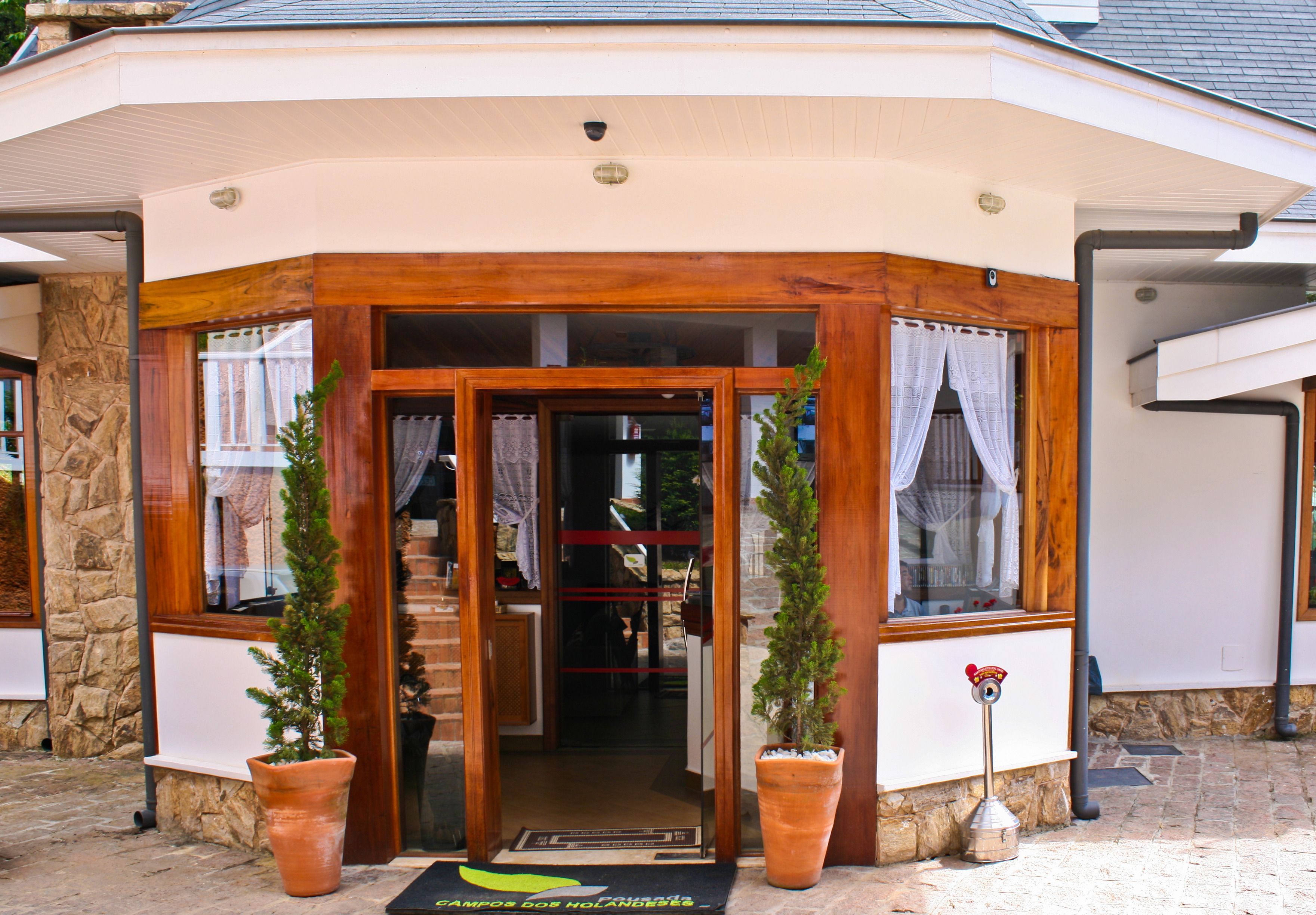 A corner entrance with a wooden frame, potted plants, and a door leading inside.