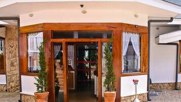 A corner entrance with a wooden frame, potted plants, and a door leading inside.