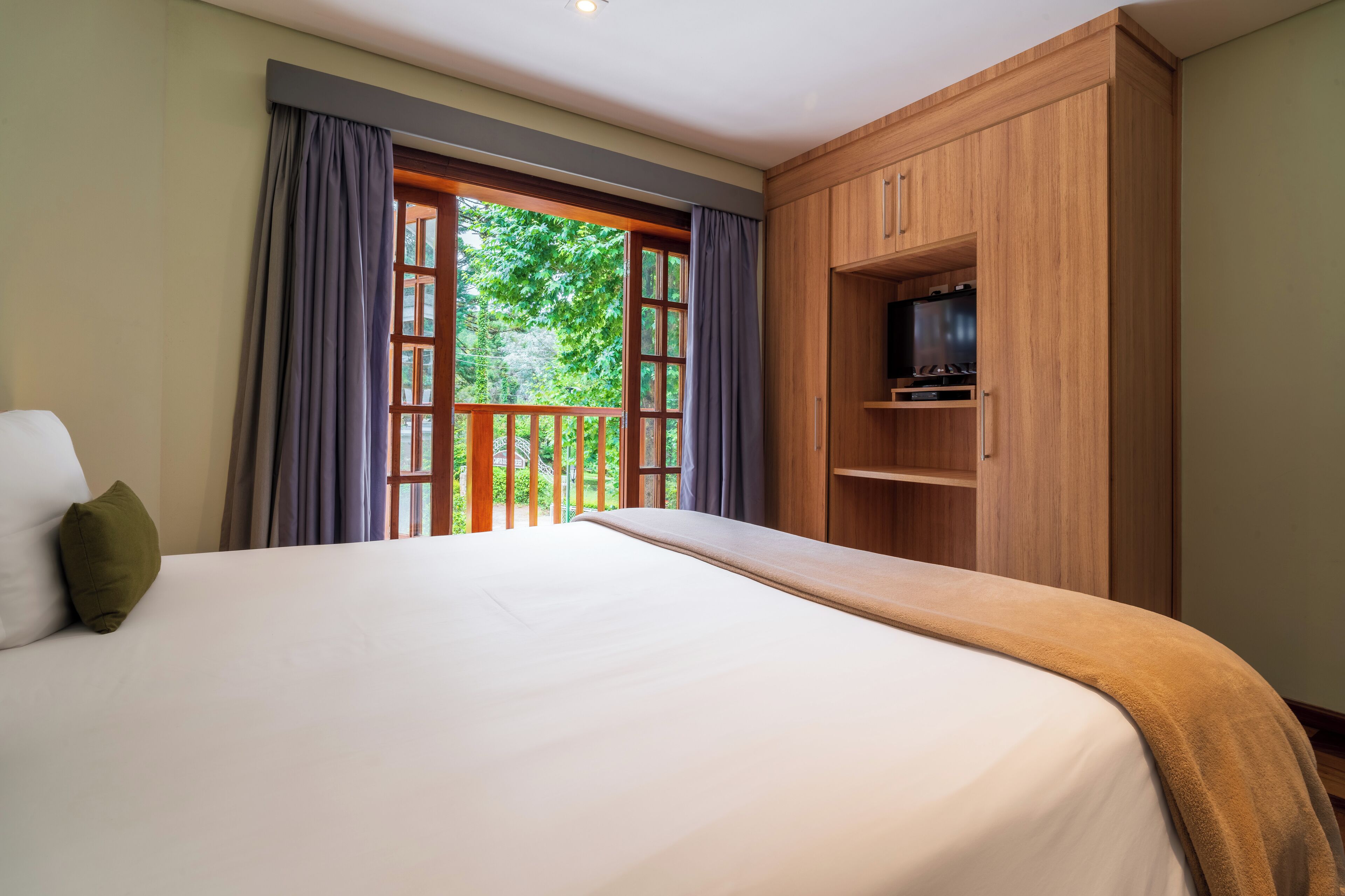 Camera da letto con un letto grande, un'armadio in legno e un ripiano per la TV.