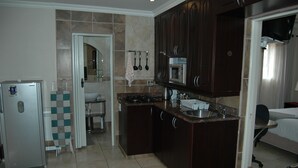 A compact hotel room with a kitchenette, including a refrigerator, microwave, and sink. - Bon a Vie B and B and Self Catering (East London)