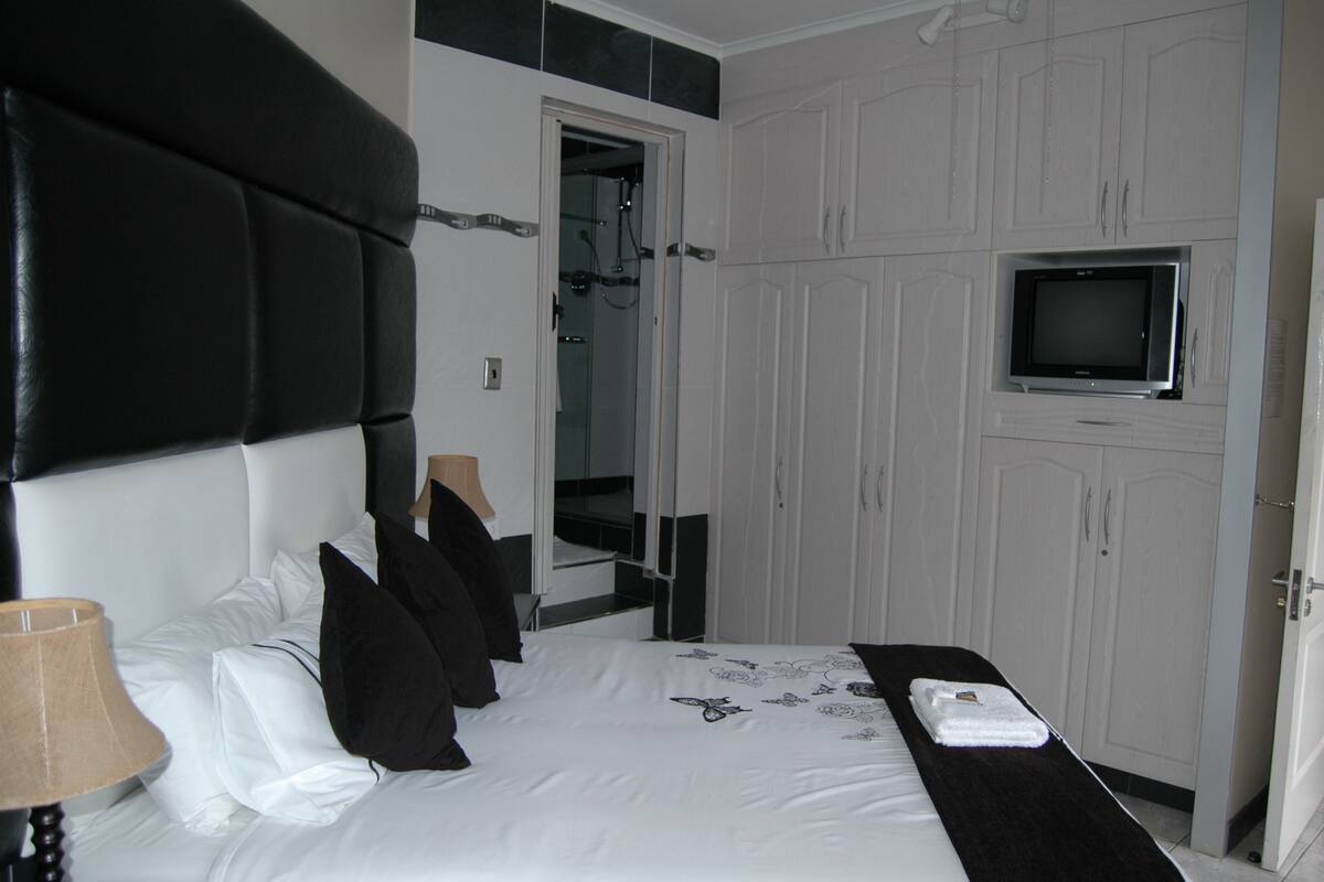 A hotel room with a bed, a TV, and a wardrobe.