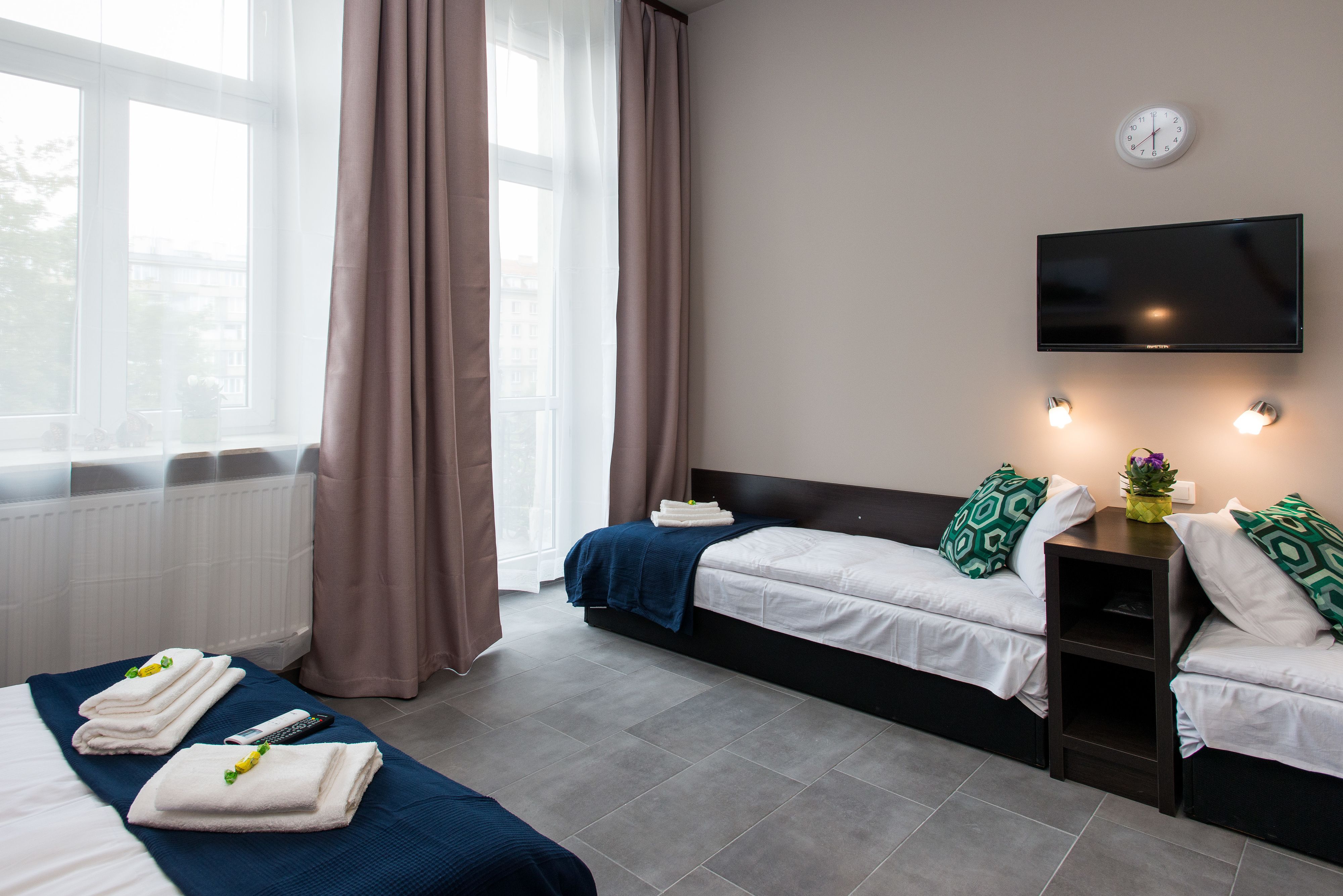 A hotel room with two beds, a TV, and a window with curtains.