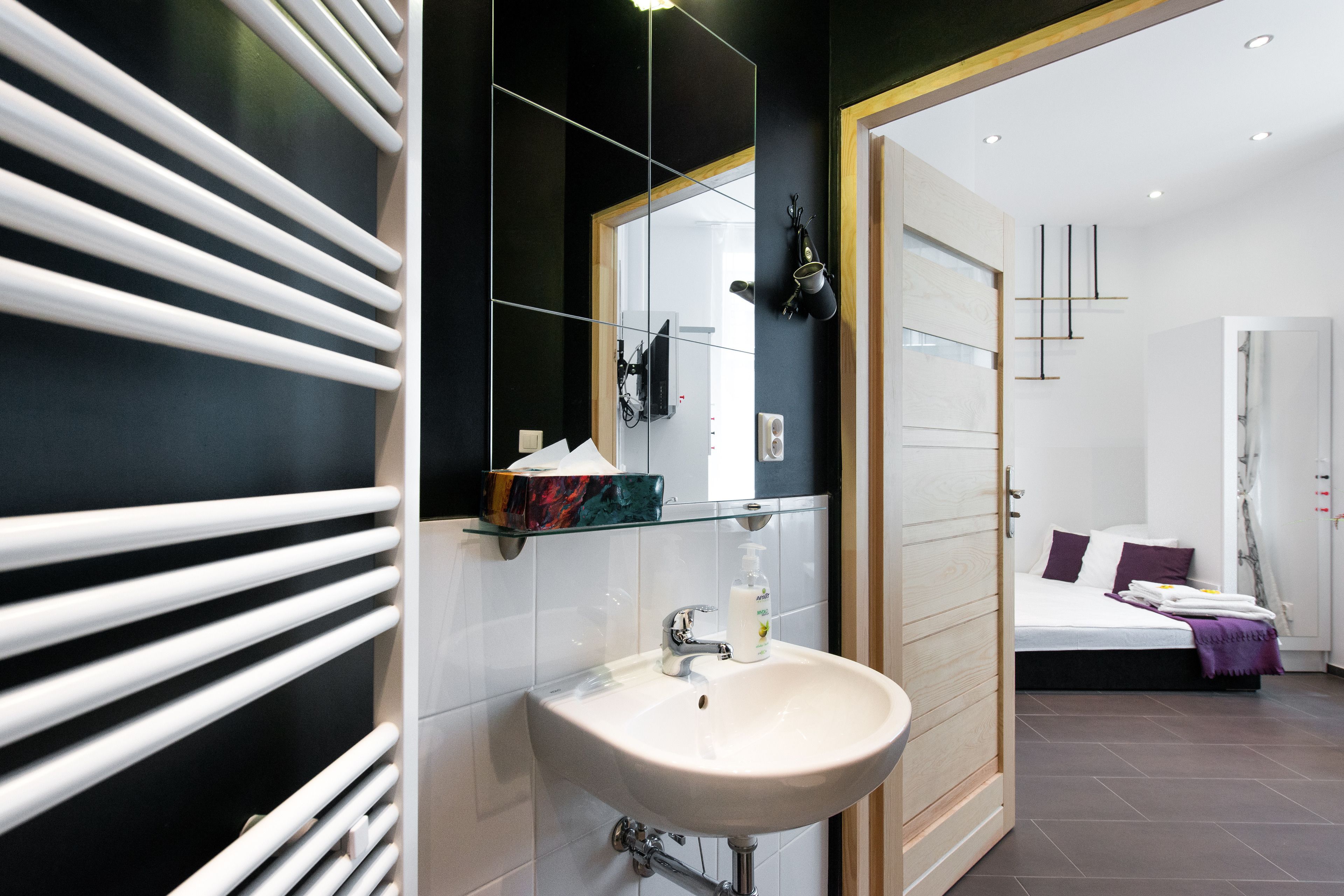 A modern bathroom with a white sink, a mirror, and a glass shelf with toiletries.