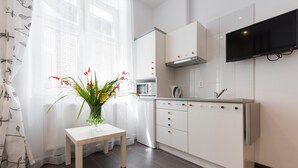 Une cuisine moderne avec des meubles blancs, un four à micro-ondes et un téléviseur fixé au-dessus du plan de travail.