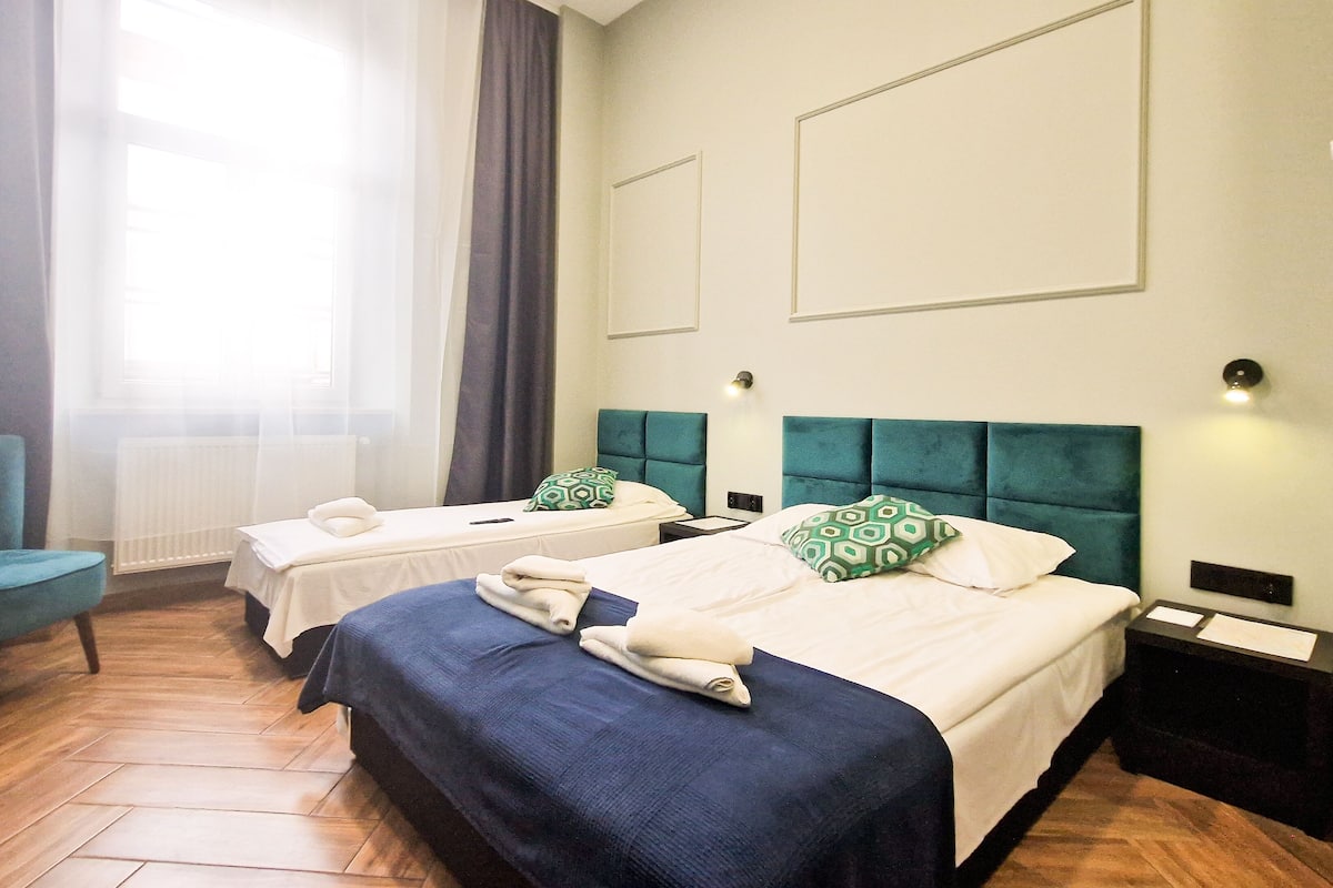 A hotel room with two beds, a chair, and a table.