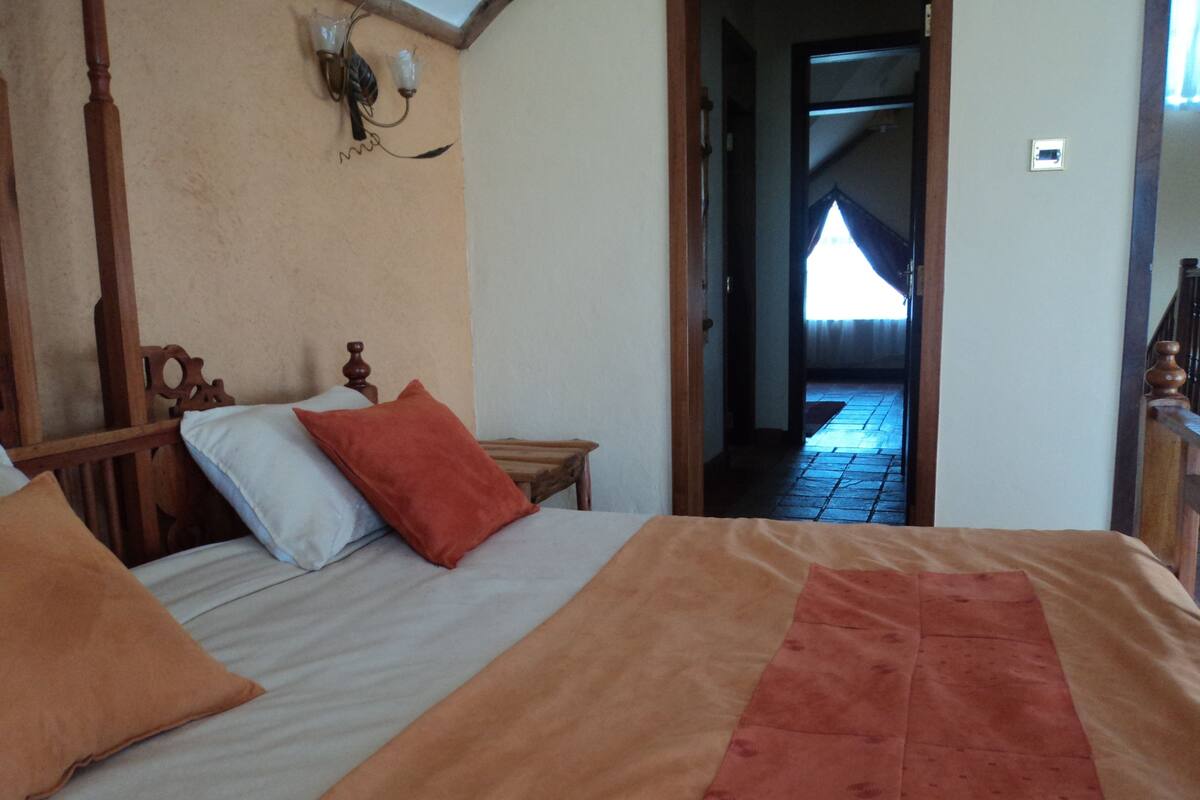 A bedroom with a wooden bed, a nightstand, and a wall-mounted lamp.