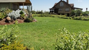 A large house with a covered porch and a well-maintained lawn. - Sangare Gardens (Mweiga)