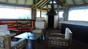 A rustic wooden interior with a kitchen area, wooden furniture, and a chimney. - Sangare Gardens (Mweiga)