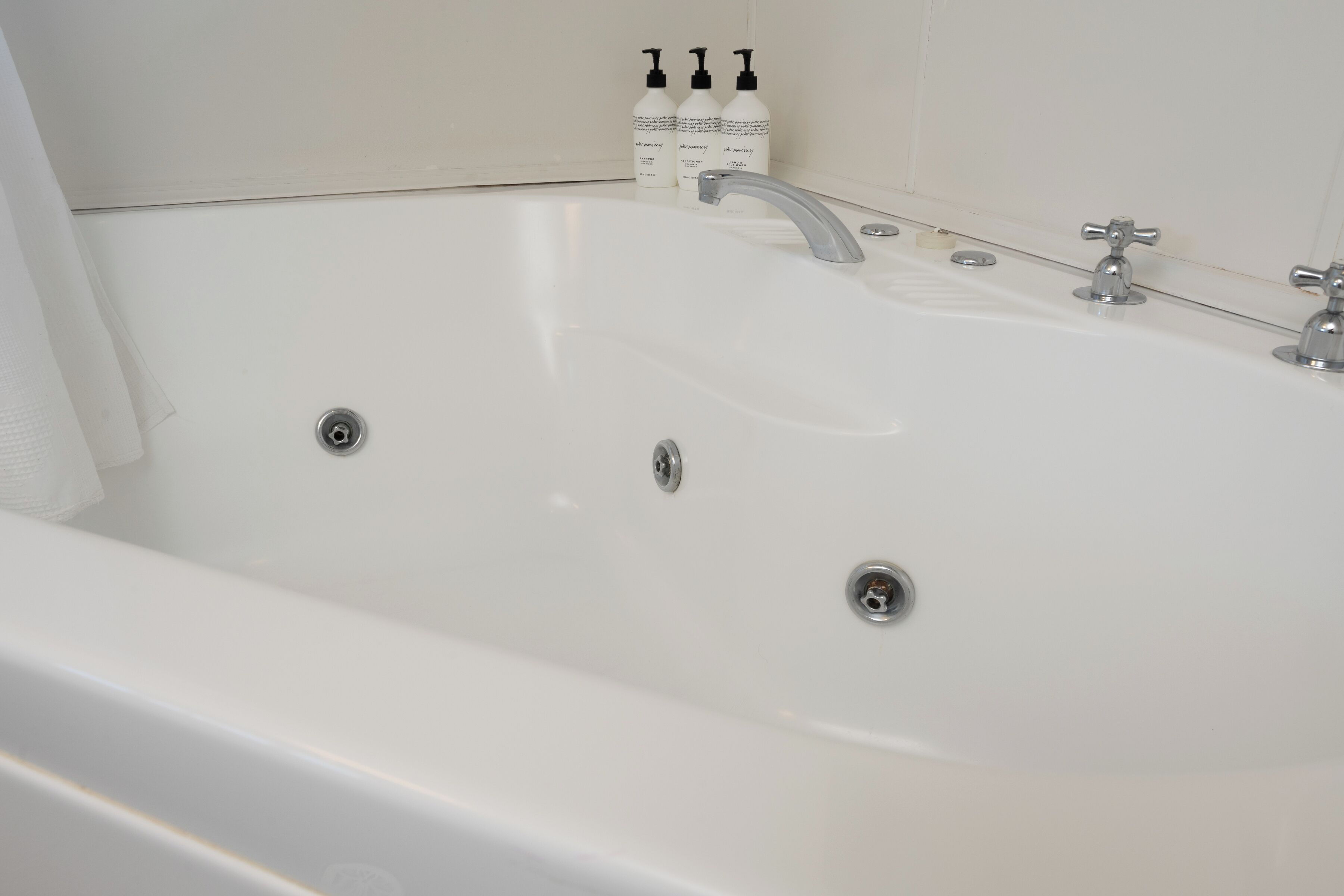 A white bathtub with two faucets and a single drain.