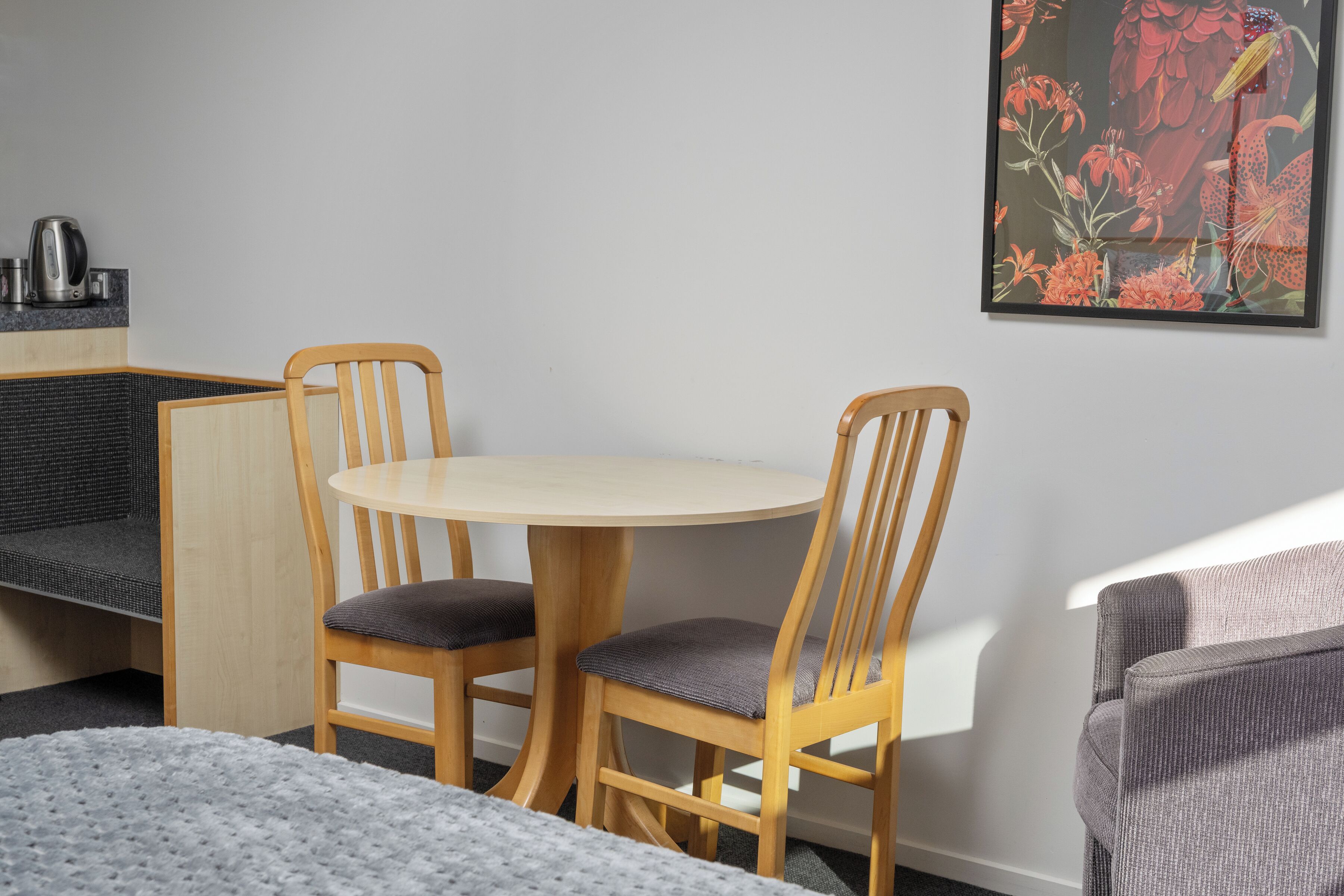 Una habitación con una mesa redonda y dos sillas de madera con asientos acolchados.