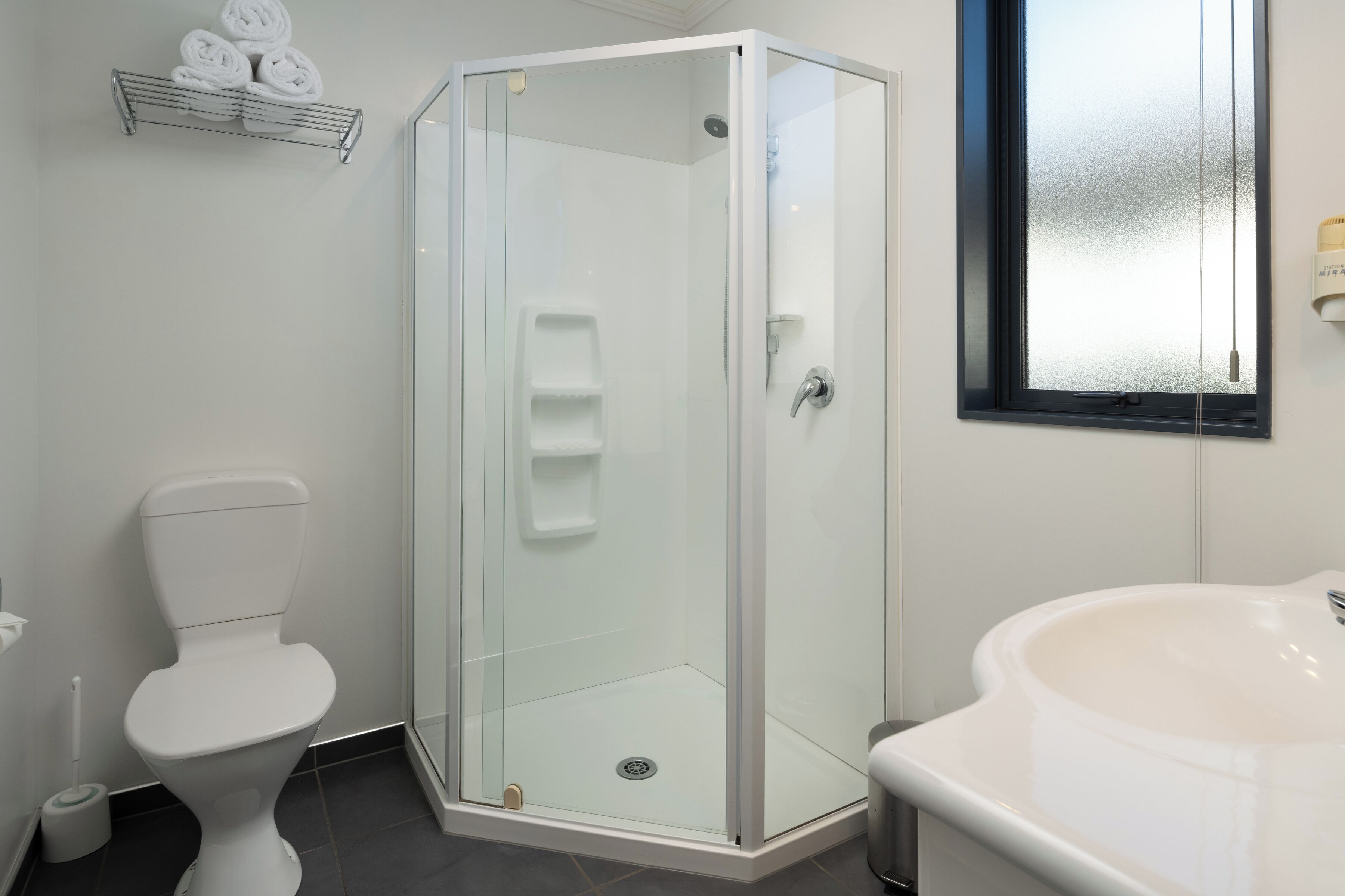 A modern bathroom with a glass-enclosed shower, a white toilet, and a large sink.
