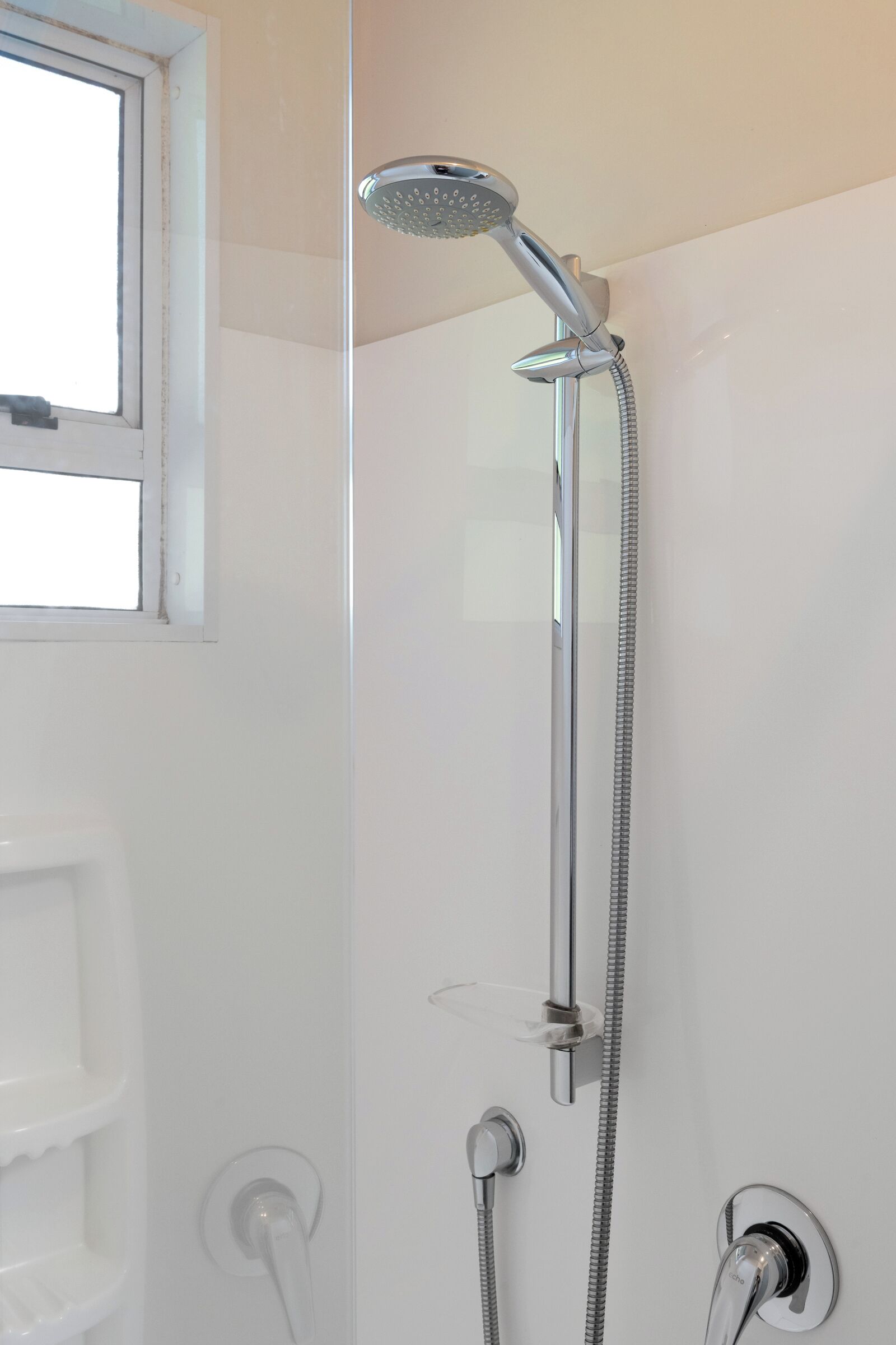 A shower with a handheld showerhead and a wall-mounted faucet.