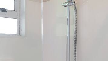 A shower with a handheld showerhead and a wall-mounted faucet.