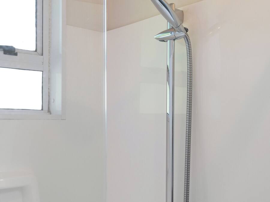 A shower with a handheld showerhead and a wall-mounted faucet.
