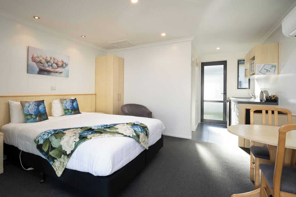 A hotel room with a bed, bedside drawers, a desk, and a chair.