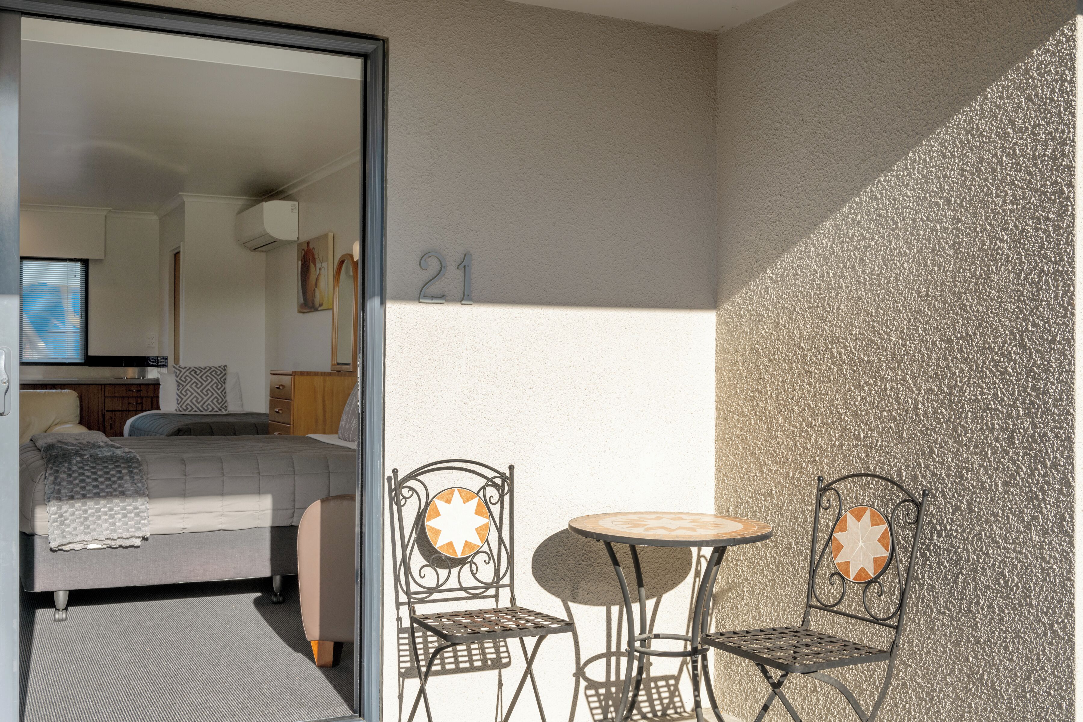 A room with a bed, a small table with two chairs, and a number '21' on the wall.