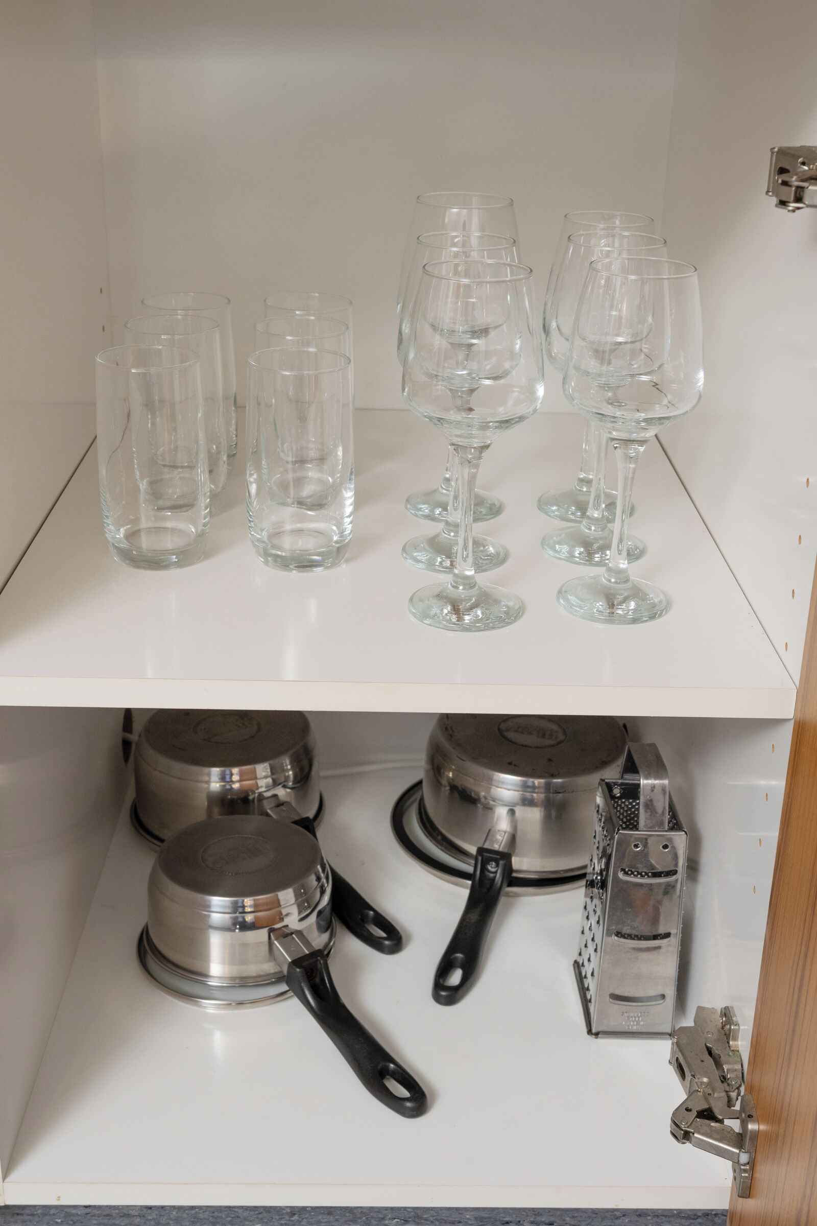 Una estantería de cocina con copas de vino y utensilios.