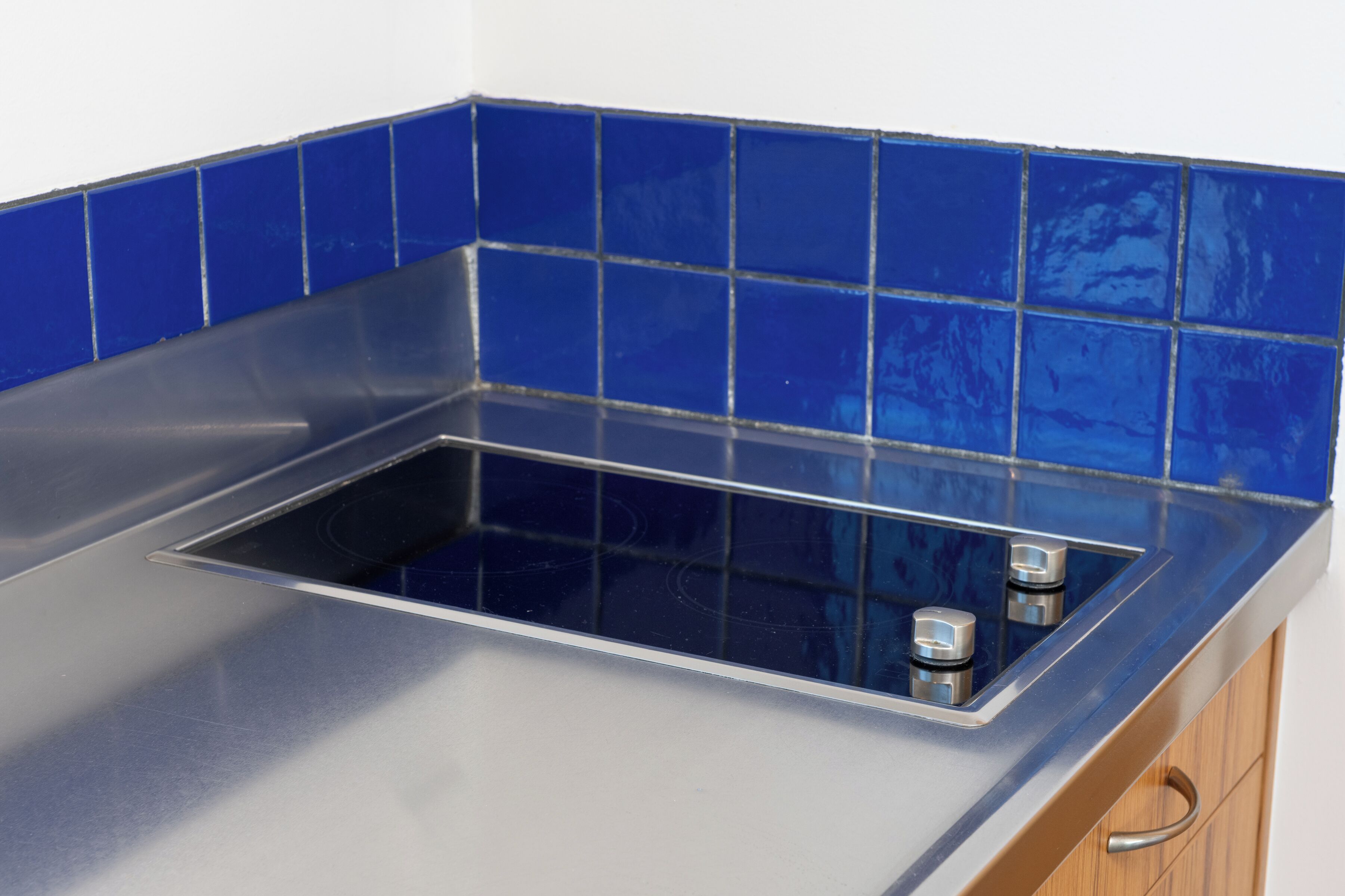 Una cocina con encimera de acero inoxidable y azulejos azules en la salpicadera.