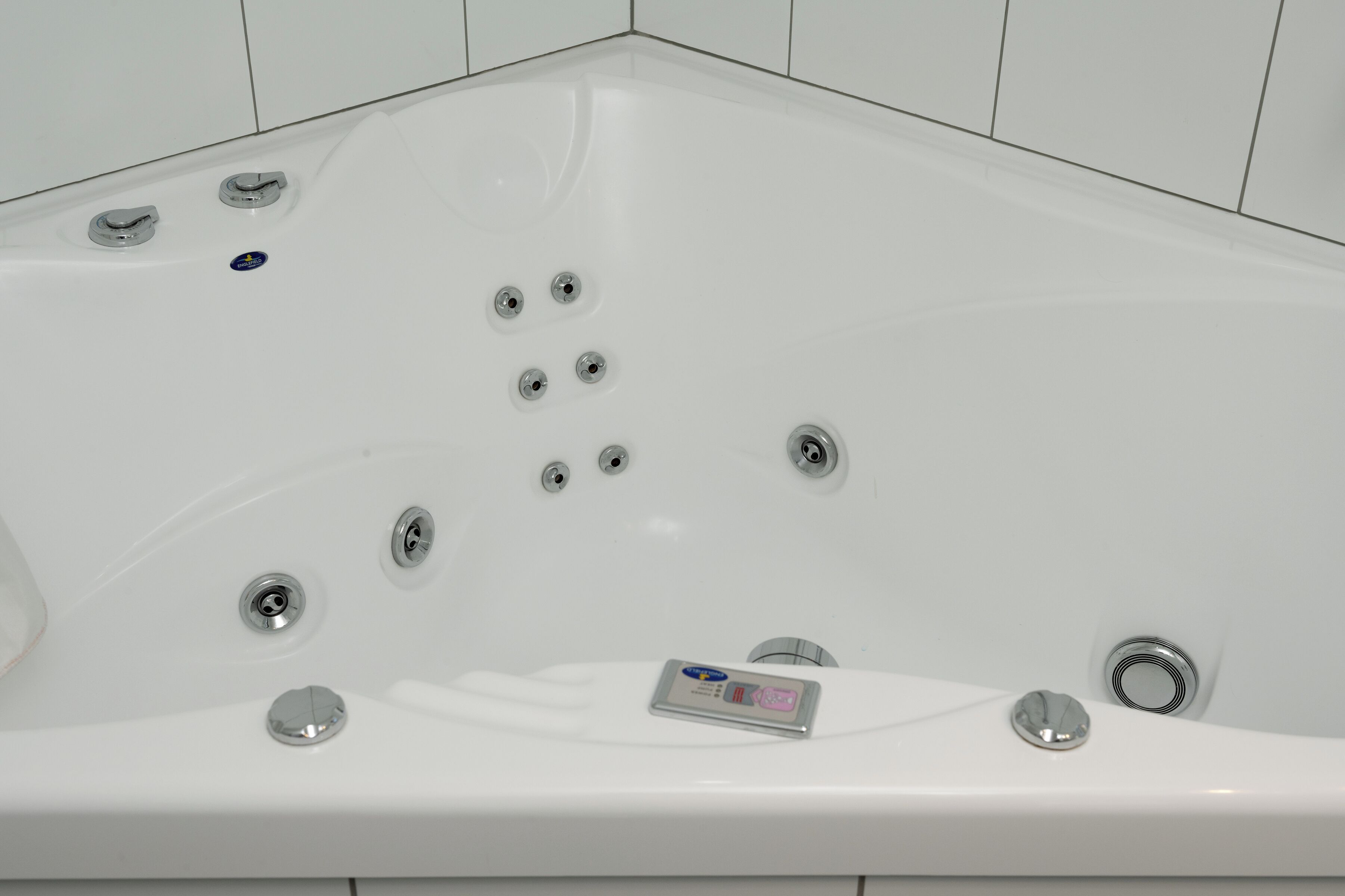A white bathtub with multiple jets and a control panel.