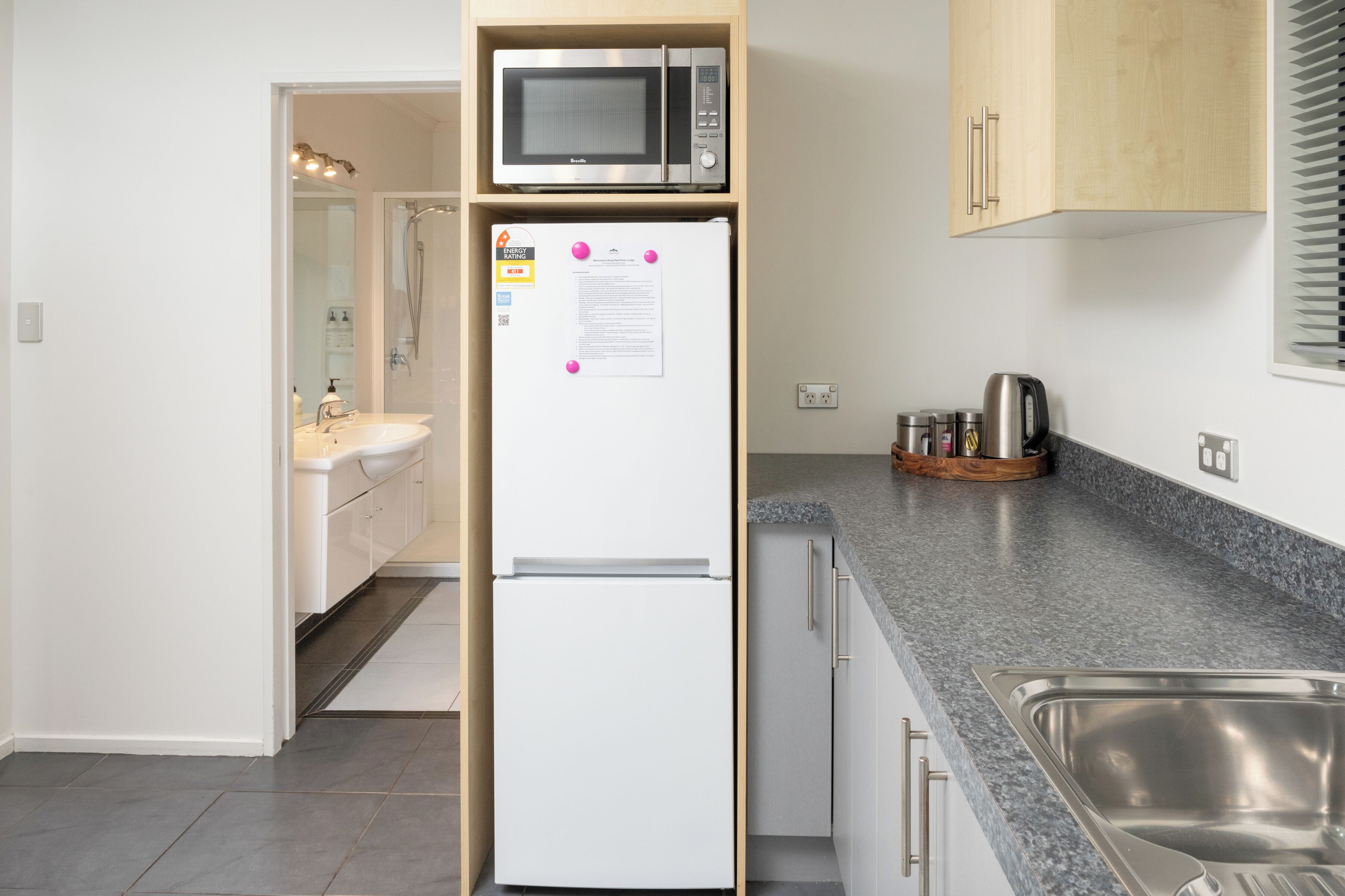 Una cocina compacta con microondas integrado, un refrigerador blanco y encimera de granito.