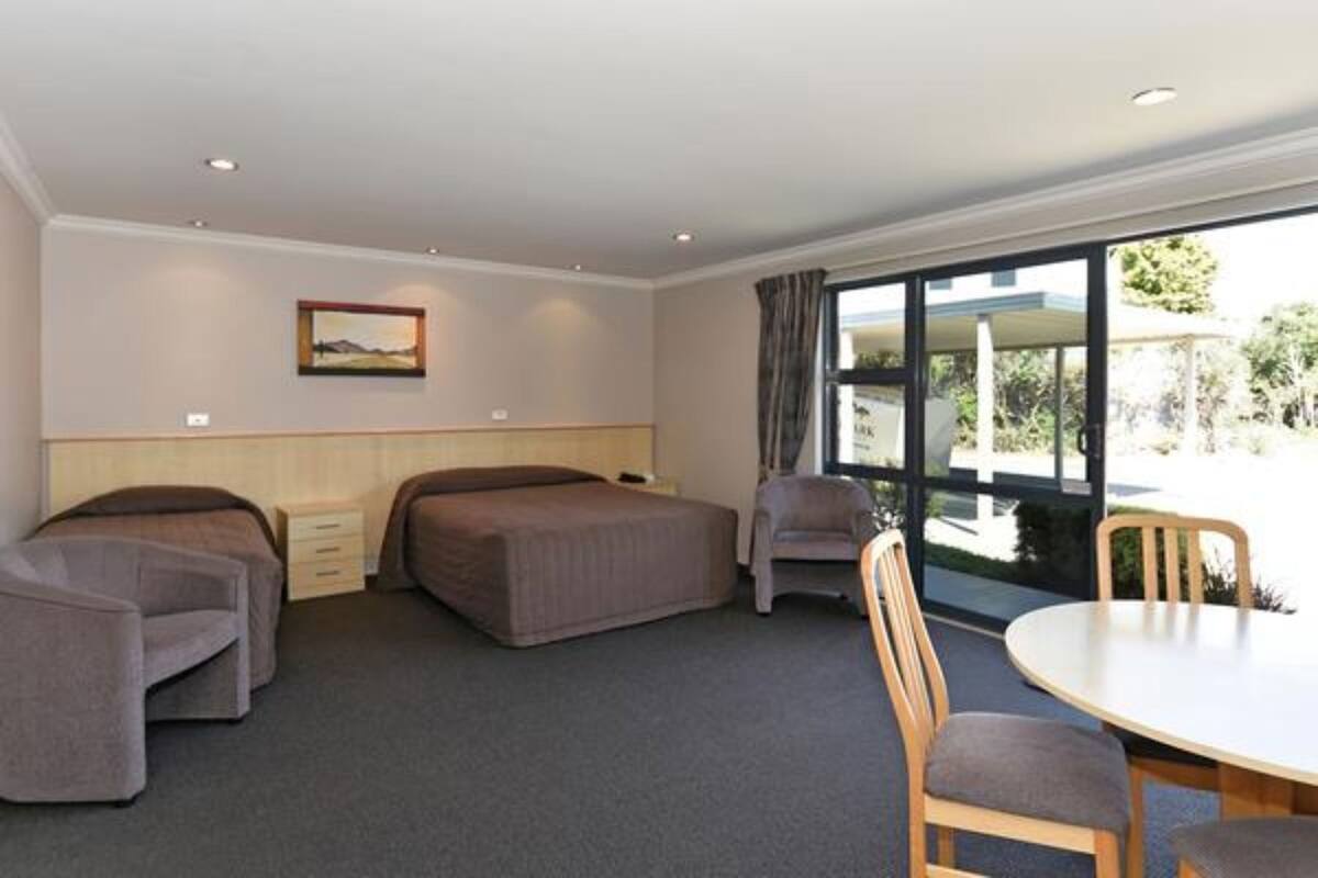 A room with two beds, a dining table, and a chair.