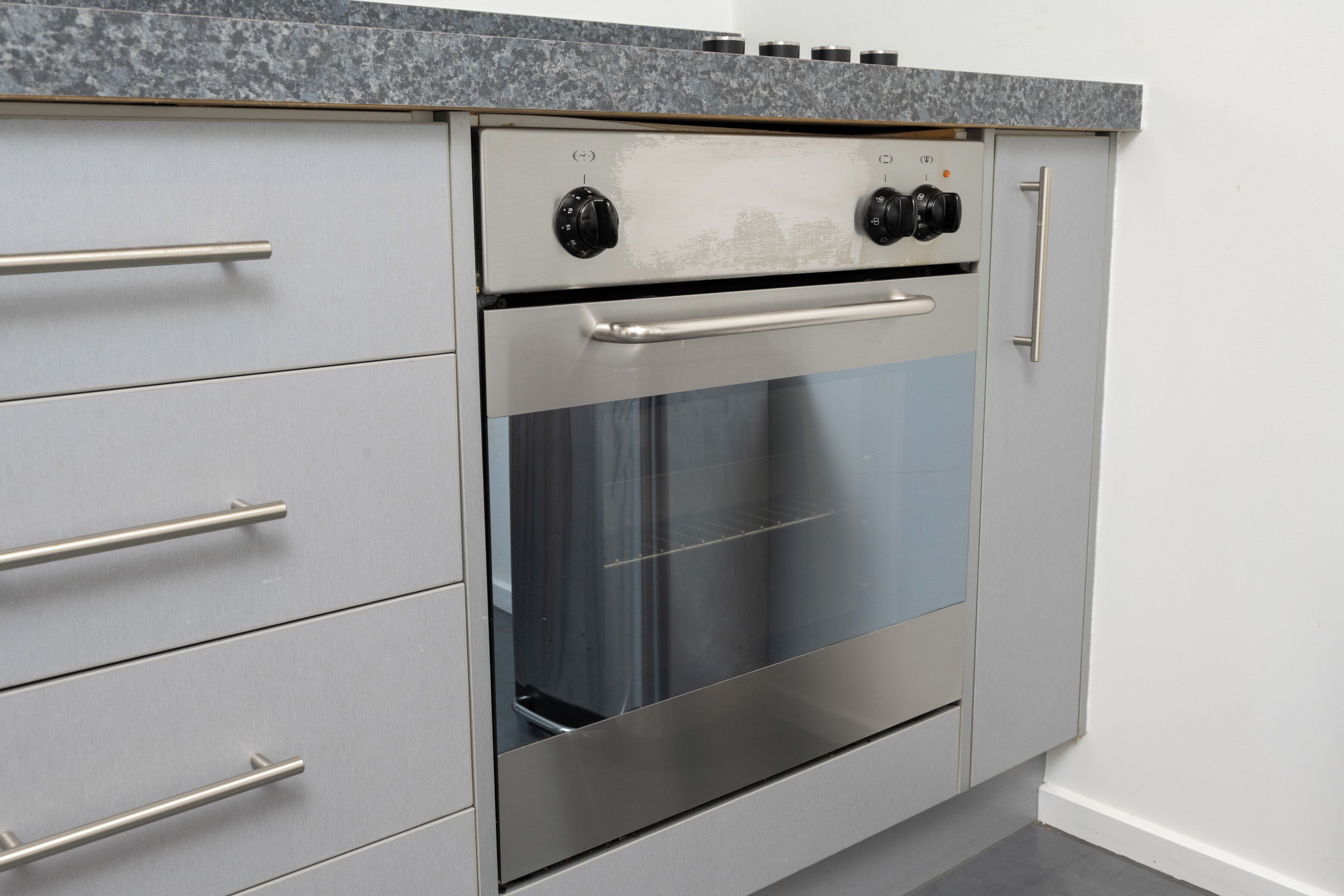 Cocina con horno de acero inoxidable, armarios grises y encimera de granito.
