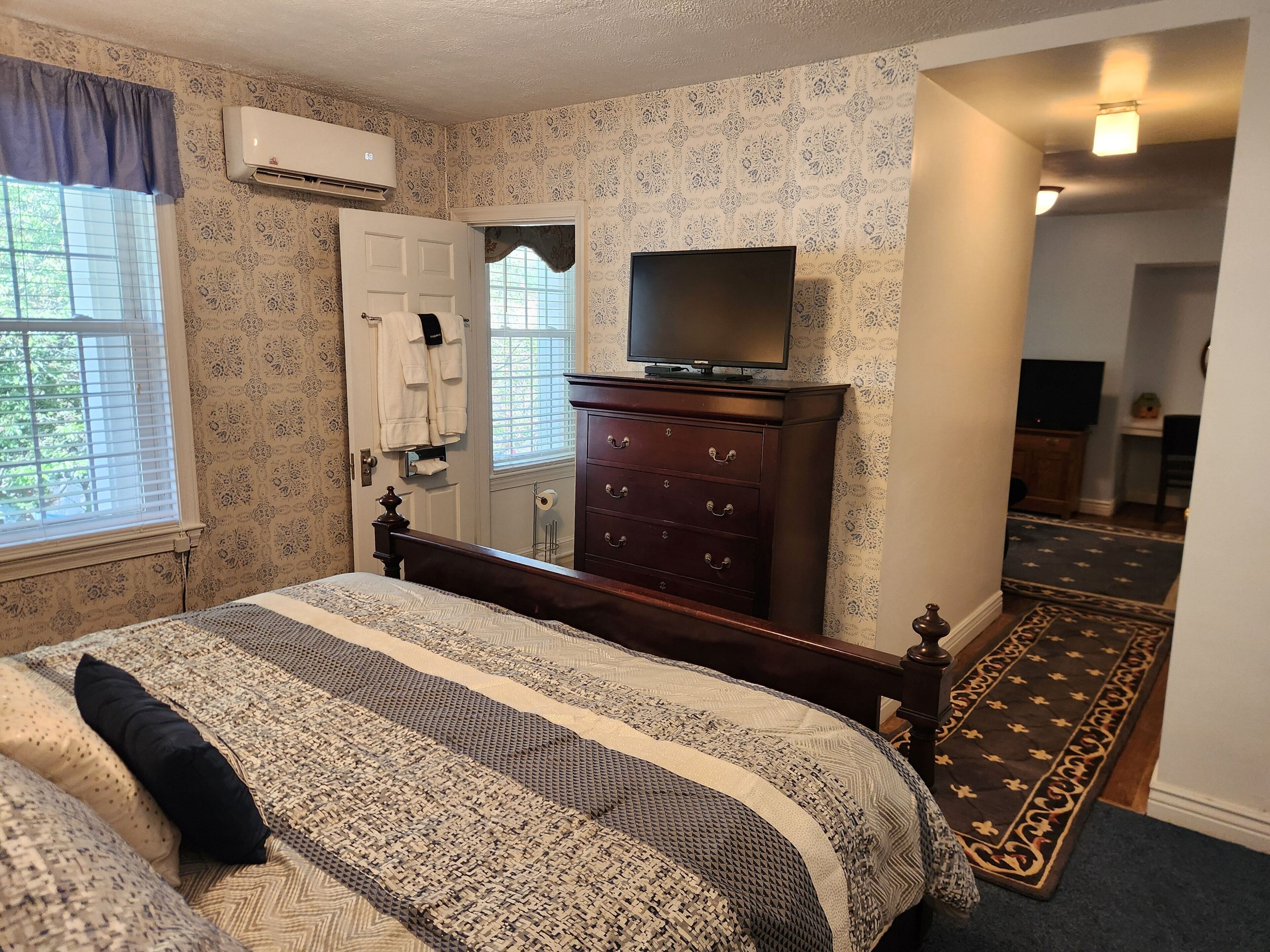 Un dormitorio con cama, cómoda, televisor y pared con diseño.