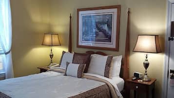 Quarto de hotel com uma cama, duas mesas de cabeceira com abajures, um quadro na parede e uma janela com cortinas.