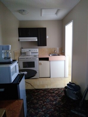 A compact kitchen with a stove, microwave, and sink.