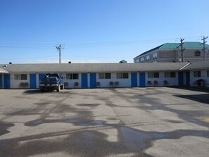 A motel with a row of rooms, a parking lot, and a blue truck parked in front.