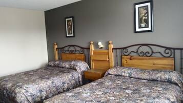 A bedroom with two wooden beds, a nightstand, and two wall-mounted lamps.